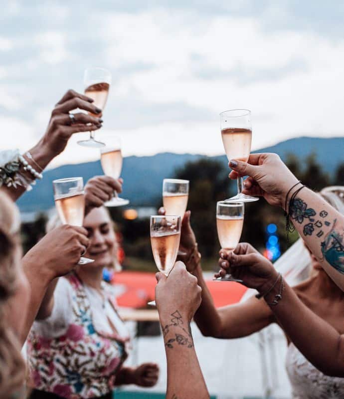 Eine Gruppe Brautjungfern prostet bei einer Hochzeit mit Champagnergläsern an.