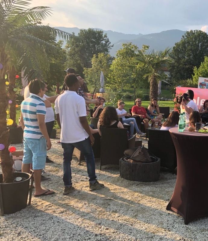 Eine Gruppe von Menschen sitzt um einen Tisch in einem Garten.