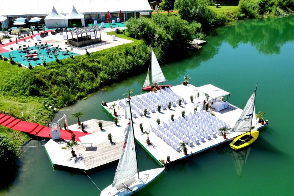 Eine Gruppe Segelboote auf einer schwimmenden Plattform mit Stühlen und einem Boot im Wasser.