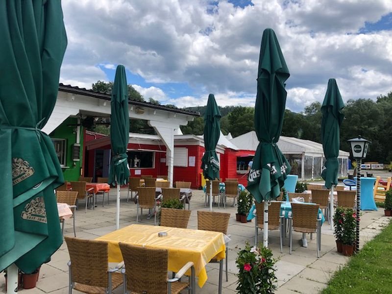Ein Restaurant im Freien mit Tischen und Sonnenschirmen.